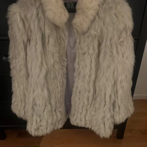 Beige pälsjacka  - Säljer en supermjuk och fluffig beige kanin pälsjacka med bred krage. Jackan har en lyxig känsla och är perfekt för dig som vill sticka ut med en trendig look. 