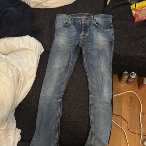 Blå jeans från Nudie Jeans, W32 - Säljer ett par klassiska blå jeans från Nudie Jeans med snygga slitningar och orangea, det passar bra till Stockholm stil samt slim jeans. Jag säljer den för 1300 för jag har använt den 1 gång. 