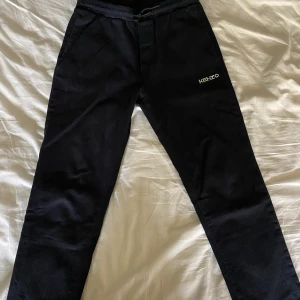 Kenzo byxor - Ett par svarta chinoliknade byxor från Kenzo i fint skick. Står storlek 152 men skulle säga att om man är runt 160 så passar dem. Nypris låg på 1300 när de köptes iaf, säljs för 700 men kan diskuteras såklart. Kom med frågor!😊