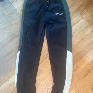 Svarta Future Projects mjukisbyxor - Svarta mjukisbyxor från Primark med grå och vita paneler längs sidorna. Byxorna har resår i midjan och en avslappnad passform, perfekt för chill dagar. Diskret logga på ena benet. Snygg och sportig look. Jag som använt dem är ca 178 och passar bra i både längd och midja. 