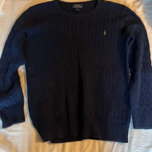 Kabelstickad ralph lauren tröja - Kabelstickad mörkblå tröja från Polo Ralph Lauren med rund halsringning och grönt broderat logotyp på bröstet. Perfekt nu till vintern för dig som vill se fräsch ut;) storlek S passar dig som är 175-180 skick 9/10