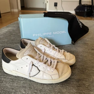 Philippe Model vita sneakers strl 43 - Snygga vita sneakers från Philippe Model i storlek 43. Skorna har detaljer i svart på hälen, beige mocka på tungan och tåpartiet samt vit skinnpanel med logotyp på sidan. Klassisk platt sula och snörning. Perfekta för en stilren och trendig look. Skorna är ändå i fint skick, kostar 3600 nypris o jag säljer dem då för 1000! Om du har minsta funderingen så är det bara o skriva. Kvitto på email finns o allt. Vill bara komma av med dem