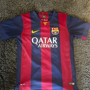 FC Barcelona Neymar Jr matchtröja S - Säljer en FC Barcelona matchtröja från Nike, Neymar Jr #11. Tröjan är kortärmad och har klassiska blå och röda vertikala ränder, med gula detaljer och klubbmärke på bröstet. Materialet är Dri-Fit polyester. Matchtröjan är den från säsongen 14/15.