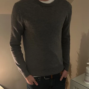 Grå merinoulltröja  - Säljer en stilren grå tröja från These Glory Days i mjuk merinoull. Klassisk rund halsringning och långärmad modell, perfekt för lager-på-lager. Enkel och clean look som funkar till jeans eller chinos. 