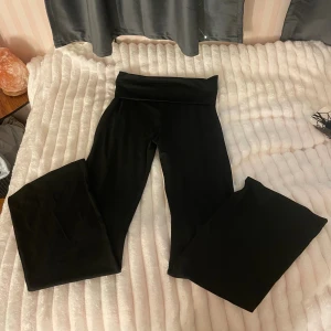 Svarta wide yoga pants - Säljer ett par svarta yoga pants med bred linning och riktigt skön stretch. Byxorna har ett wide fit och är tillverkade i mjukt syntetmaterial som sitter bekvämt mot kroppen. Byxorna är helt nya jag har inte använt dom nått.