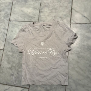 Grå croppad t-shirt Leisure Club - Cropped tröja från H&M. Endast använd ett par gånger och därför defektfri ❕❕Skriv om frågor osv och kolla gärna min profil