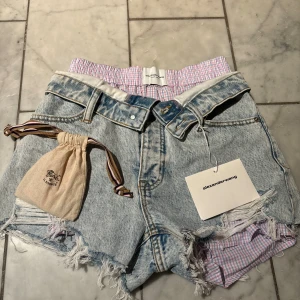 Alexander Wang jeansshorts med en nyckelring från il bisonte  - HELT NYA! orginalpris för endast shortsen: ca 7000kr Snygga ljusblå jeansshorts från Alexander Wang med hög midja och råa, fransiga kanter. Insidan har ett rosa och lila rutigt tyg som syns vid bensluten och midjan! Kommer med en nyckelring från märket il bisonte ❕ pris går att diskuteras och Skriv om frågor osv och kolla gärna min profil