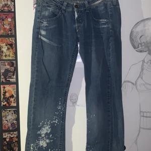 Blå jeans med blekta detaljer - Säljer ett par blå jeans med coola blekta detaljer och stänk på benen. Klassisk femficksmodell med raka ben och normal passform. Jeansen har slitningar och ljusare partier framtill och på bakfickorna. Vet tyvärr inte märke men det står Sakura på lappen. Storleken är 27/32. Finns tecken av användning längst ner på benen. Skriv för mer bilder