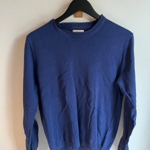 Blå stickad tröja  - En stilren blå stickad tröja  med rund halsringning och ribbade muddar. Perfekt för lager-på-lager och funkar året runt. Enkel design som är lätt att matcha med jeans eller kjol.