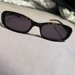 CHIMI Tortoise solglasögon brun - Snygga solglasögon från CHIMI med rektangulär form och tortoise-mönstrad båge i bruna och svarta toner. Glasen är mörka och bågen är tillverkad i syntetmaterial. Perfekt accessoar för att lyfta din stil.