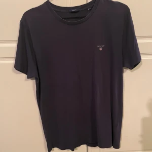 Mörkblå Gant t-shirt - Säljer denna mörkblåa Gant t-shirt. Den är i hyfsat skick men saknar storlekslapp vilket betyder att jag inte vet exakt vilken storlek den är, men passar M/L. Nypris ligger på 600kr. Hör av er vid eventuella funderingar!