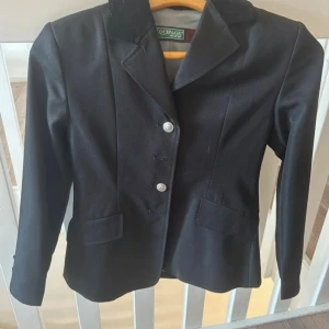 Svart ridtävlingkavaj .  - Svart ridtävlingskavaj från Equipe. 2 knappar saknas på framsidan (se bild 1), men det är inget som påverkar eller stör. Använd väldigt sparsamt och är i väldigt fint skick