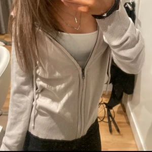 Beige ziphoodie med huva - Säljer en beige hoodie med dragkedja och huva. Tröjan har långa ärmar och ribbade muddar vid ärmslut och nederkant. Perfekt för chill dagar och enkel att matcha med jeans eller leggings.