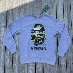 Grå sweatshirt från BAPE med camo-print - Säljer en grå sweatshirt från BAPE helt ny aldrig använt säljer den på grund av att den inte passar mig säg gärna till om du har någon fråga eller om det är något som du undrar över 