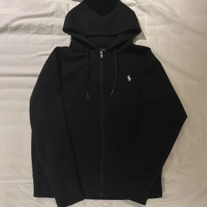 Svart hoodie från Polo Ralph Lauren - Svart hoodie från Polo Ralph Lauren i storlek S. Använd väldigt få gånger PGA att tröjan var för liten för mig. Om det är några funderingar eller saker jag kan hjälpa till med är det bara att skriva 