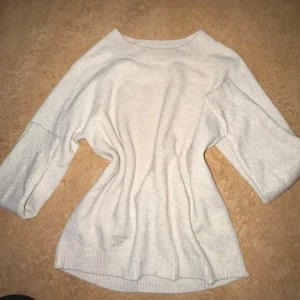 Ljusbeige stickad tröja från Vero Moda - Säljer en ljusbeige stickad tröja från Vero Moda. Tröjan har en avslappnad passform och rund halsringning. Perfekt för dig som gillar enkel och stilren design med lite extra volym i ärmarna.