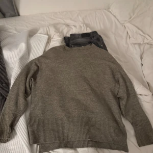 Beige stickad tröja från H&M - Mysig beige stickad tröja från H&M i storlek M. Tröjan har ribbade muddar, rund halsringning och slits i sidorna för en chill vibe. Perfekt för lager-på-lager och passar till allt.