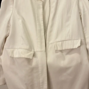 Vit jacka med dragkedja och fickor - Snygg vit jacka med rak passform, dragkedja framtill och två stora fickor med lock. Jackan har en stilren look och är perfekt för dig som gillar minimalistisk stil.