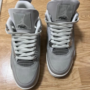 Nike Air Jordan 4 Retro Metallic Silver - Säljer ett par Nike Air Jordan 4 Retro i metallic silver och grått. Skorna har snygga silvriga detaljer, meshpaneler och klassisk snörning. Ovandelen är i en mix av mocka och syntet, med ikonisk Jumpman-logga på plösen. Perfekta för dig som vill sticka ut med stilrena sneakers.