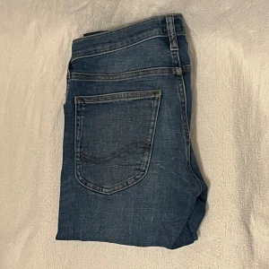 Lee jeans  - Säljer ett par blå Lee Luke jeans i skinny fit, storlek W28 L32. Jeansen har klassisk femficksdesign, snygga slitningar och Lee-logga på bakfickan. Passformen är smil/straight