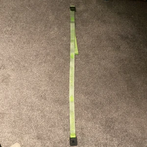 Grönt capeesh bälte med broderade detaljer - Snyggt grönt bälte med broderade siffror och lövdetaljer i ljusgrönt. Materialet är slitstark polyester och designen är rak och modern, perfekt för att ge outfiten en unik touch.