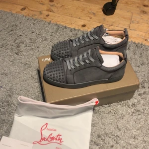 Grå Christian Louboutin  - Säljer ett par gråa sneakers från Christian Louboutin. Skorna har snörning och en låg profil, perfekt för dig som vill sticka ut med exklusiv streetstyle. Skorna är använda 2 gånger och är i perfekt skick. Pris går att diskutera vid snabbare affär.  