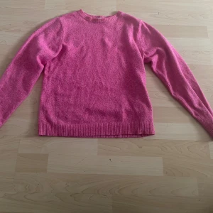 Rosa stickad tröja från Vero Moda - Mysig rosa stickad tröja från Vero Moda Girl med rund halsringning och ribbade muddar vid ärmslut och nederkant. Perfekt för lager-på-lager och enkel att matcha med jeans eller kjol.