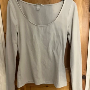 Vit långärmad urringad topp - En vit långärmad topp med urringad där fram, från h&m