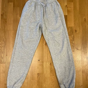 Gråa mjukisbyxor från SOC  - ✨ Ljusgråa mjukisbyxor – minimalistisk design ✨ 	•	👖 Storlek: XS – Mått: Midja 60cm/ Längd från toppen till botten 95cm.   	•	🩶 Färg: exklusiv ljusgrå, en tidlös bas i garderoben 	•	🌟 Skick: Nästan nyskick – endast använda några få gånger 	•	💤 Premiumkänsla med mjukt material som andas komfort 	•	👜 Perfekt för en modern streetstyle-look eller en clean athleisure-outfit  💸 Endast 59 kr – få den lyxiga looken till ett oslagbart pris ✨