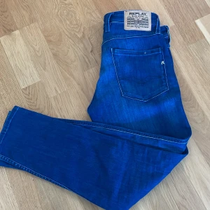 Blå Replay Anbass jeans herr - Snygga blå jeans från Replay, modell Anbass. Klassisk femficksdesign med Replay-logga på myntfickan och bakficka. Jeansen har en modern passform och är tillverkade i mjukt denimtyg som sitter skönt hela dagen. Helt nya 