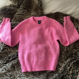 Rosa stickad tröja från Lindex XS - Mysig rosa stickad tröja från Lindex i storlek XS. Tröjan har rund hals, ribbade muddar och långärmade ärmar. Perfekt för dig som gillar färg och vill ha en skön och fluffig tröja till hösten eller vintern.
