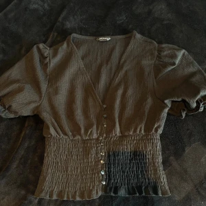 Topp  - Söt topp med knappar och puffiga axlar. Köpt från Sellpy men aldrig använd av mig. Från monki 