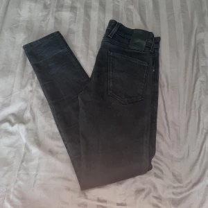 Svarta jeansbyxor från Replay Anbass - Säljer ett par svarta Replay Anbass jeans med klassisk femficksdesign och diskret Replay-logga vid fickan. Jeansen har normal passform och är tillverkade i stretchigt material för extra komfort 30w32l.