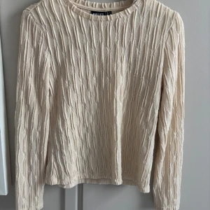 Beige ribbad långärmad tröja - Säljer en beige långärmad tröja från Pieces med ribbad struktur och diskret mönster. 