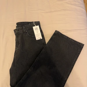 Svarta wide jeans från Jack & Jones - Säljer ett par svarta jeans från Jack & Jones med breda ben och klassisk femficksdesign. Jeansen har hög midja och är tillverkade i ett mjukt bomullsmaterial med lite stretch. Perfekta för dig som gillar en avslappnad och trendig look.