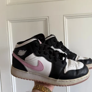 Nike Air Jordan 1 Mid svart/vit/rosa - Nike Air Jordan 1 Mid i svart, vitt och ljusrosa.  Väl använda men i ett bra skick 