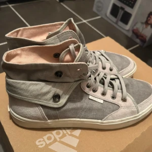 Grå höga sneakers från Esprit, strl 39/40 - Snygga höga sneakers från Esprit i grått tyg med ljusrosa foder. Skorna har snörning och vikbar kant med tryckknappar för en cool look. Perfekta för dig som gillar streetstyle och vill ha något unikt till vardagsoutfiten.