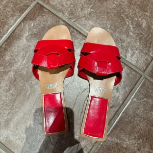 Röda sandaler med fyrkantig tå från Zara - Säljer ett par röda sandaler från Zara med snyggt flätad remdesign och fyrkantig tå. Aldrig använda.