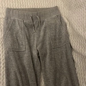 Grå mjukisbyxor Juicy Couture XS - Gråa mjukisbyxor från Juicy Couture i XS  säljer dessa byxor för att det finns en fläck på sidan av byxorna (i sista bilden), köpte dessa här på Plick och säljaren sa inte att det fanns en fläck, hon tog inte bild på fläcken heller, när byxorna kom såg jag fläcken och tänkte skriva men kontot är borta, dock inget man tänker på när man har på sig dom.