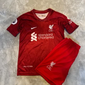 Liverpool Salah matchtröja Nike röd- storlek 164 - Liverpool FC matchtröja med M. Salah 11 på ryggen. Röd med vita detaljer, kortärmad och tillverkad i Dri-FIT material. Nike-logga, klubbmärke och sponsortryck på bröstet. Säljes tillsammans med matchande shorts med LFC-logga. Storlek 164.