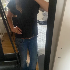 Svart blus med volangärm  - Supersöt svart blus från zalando med volangärmar och lätt rynkad midja. Blusen har rund halsringning. Perfekt att styla med jeans eller kjol för en trendig look.