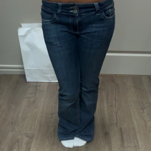 Mörkblå jeans  - Mörkblå jeans från Nelly med vita detaljer på fickorna. Jeansen har blivit väl använda, men bra omhändertagna. Längst ner på båda benen har dem gått sönder lite men det är inget man tänker på när man har på sig dem. Jeansen är i storlek 36 men har ett stretchigt material. Midjemått: 36 cm rakt över. Innerbenslängd: 81 cm💗
