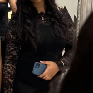 Svart spets topp från Vero Moda - Supersnygg svart spets topp från Vero Moda med långärmade transparenta ärmar och hög krage. Den har figurnära passform och vackra spetsdetaljer över hela plagget. Perfekt för dig som vill sticka ut med en elegant och trendig look. (Pris kan diskuteras)