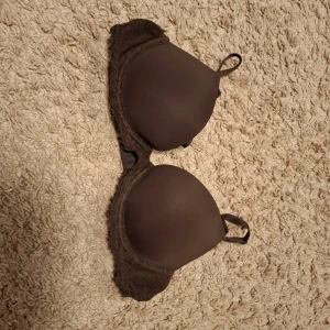 Brun push-up bh från H&M, 75A - Säljer en brun push-up bh från H&M i storlek 75A. Bh:n har släta kupor och spetsdetaljer längs kanterna för en snygg look. Axelbanden är justerbara och materialet är mjukt polyester med elastan för skön passform. Skulle säga att den är mer AA cupa. Säljer då den e för lite.