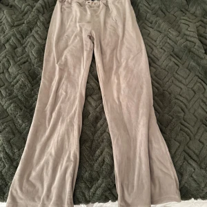 Beiga vida byxor från Gina Tricot - Snygga beiga byxor från Gina Tricot i mjukt, sammetsliknande material. Modellen är vid med utsvängda ben och resår i midjan för extra komfort. Perfekta för en chill och trendig look.