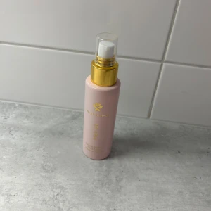 Heart for Heart Hair Oil rosa flaska - Snygg rosa flaska med guldpump från Heart for Heart, innehåller hair oil. Flaskan är smal och har en genomskinlig plastkork. Perfekt att ha framme på sminkbordet för en lyxig känsla. 95% kvar