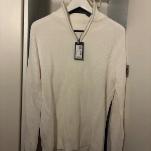 Vit ribbad half zip stickad tröja - Vit stickad tröja med ribbad struktur och half zip-dragkedja i halsen. Från lager 157 i storlek S. Oanvänd med prislappen kvar!