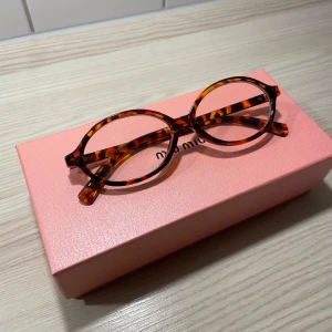 Runda ikoniska glasögon  - Snygga runda glasögon som liknar den ikoniska miumiu glasögonen med ett trendigt sköldpaddsmönster. Perfekta för att ge din stil en extra touch av elegans. Kommer i en kartong med en duk. Boxen på bilden ingår inte, endast för bildens skull.