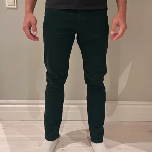 Mörkgröna slim fit byxor från H&M - Snygga mörkgröna slim fit byxor från H&M i storlek 32. Byxorna har en smal passform och är tillverkade i ett mjukt bomullsmaterial. Perfekta för dig som gillar en stilren och modern look.