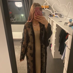 Beige ribbad långklänning med spetskimono - Svart transparent kimono med blommigt spetsmönster och vida ärmar. Perfekt för dig som vill ha en cool sommar look. One sise